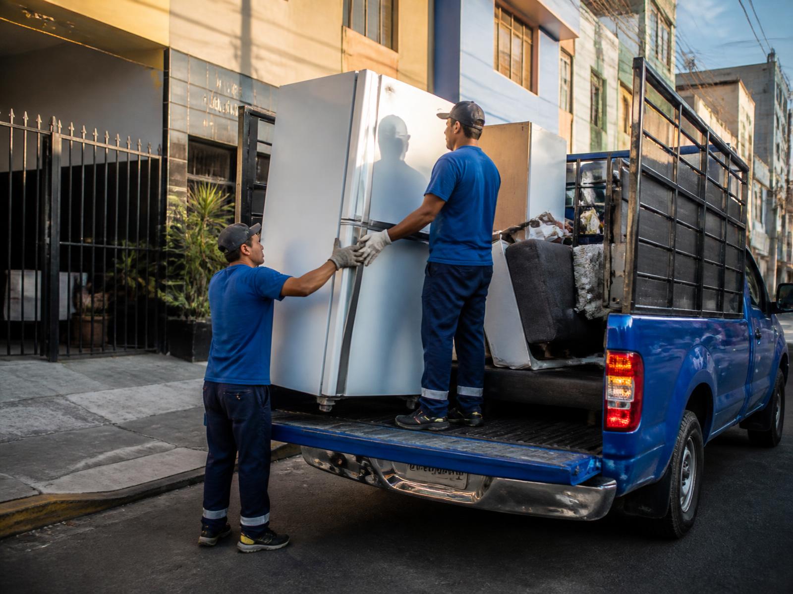 Transportistas cargando un refrigerador en una pickup azul
